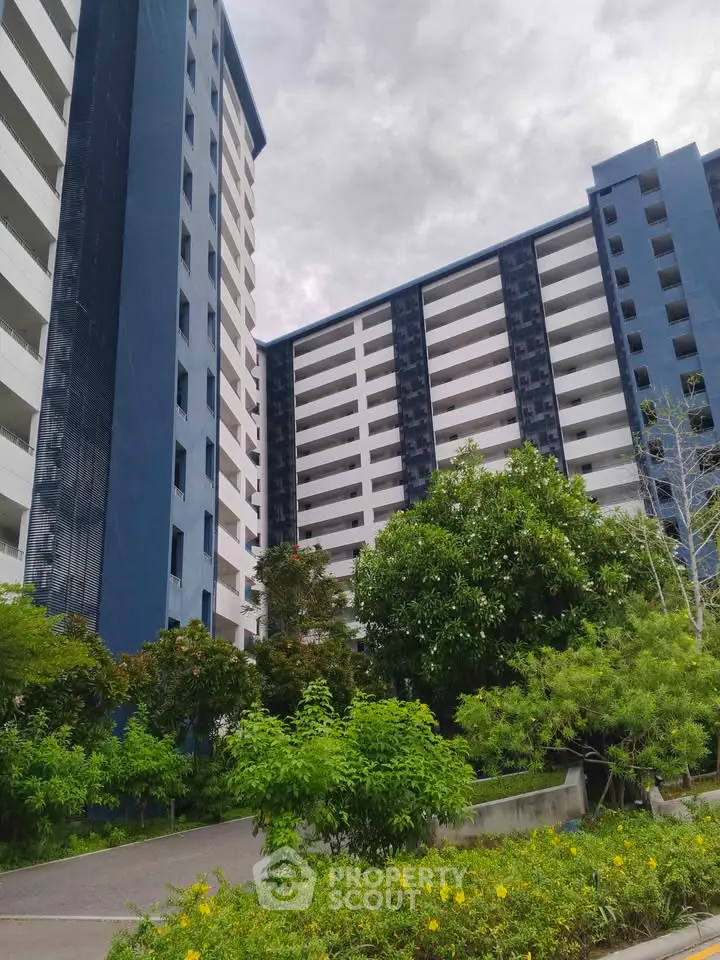 Modern high-rise residential building with lush greenery and vibrant landscaping.