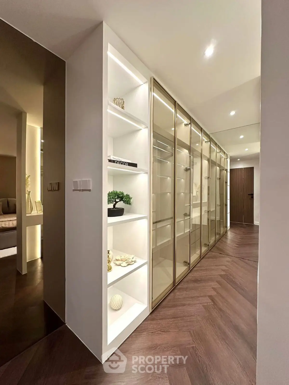 Luxurious hallway with elegant shelving and glass-fronted storage, featuring modern lighting and sleek design.