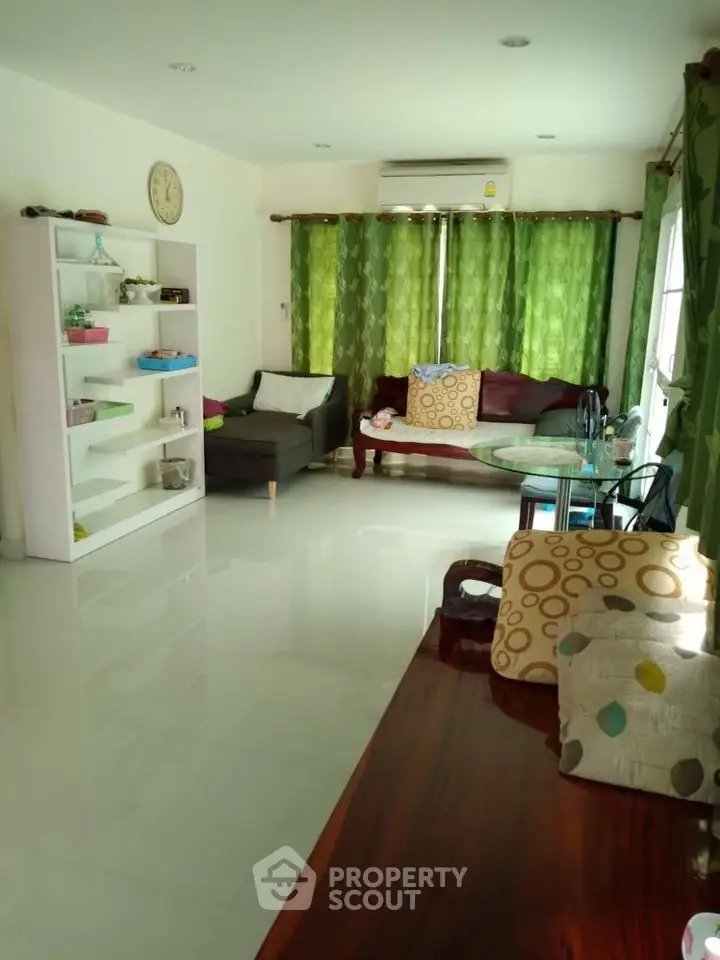 Spacious living room with modern decor and green curtains, perfect for relaxation and entertaining.