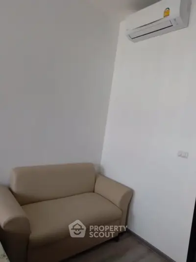 Cozy small living room with beige sofa and wall-mounted air conditioner.