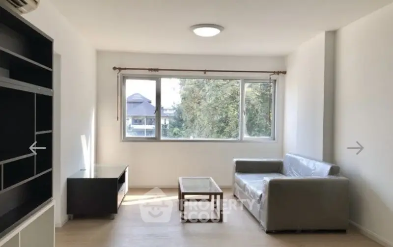 Bright living room with large window and modern furniture in a cozy apartment.