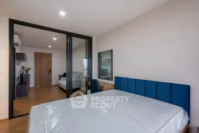 Modern bedroom with blue headboard and sliding glass doors leading to a cozy living area.