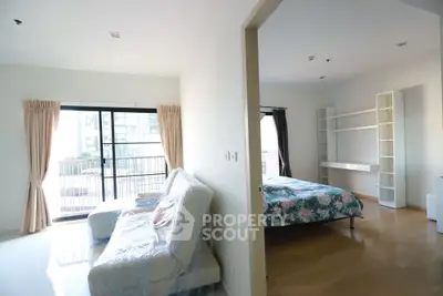Spacious bedroom with balcony access and modern furnishings in a bright apartment.