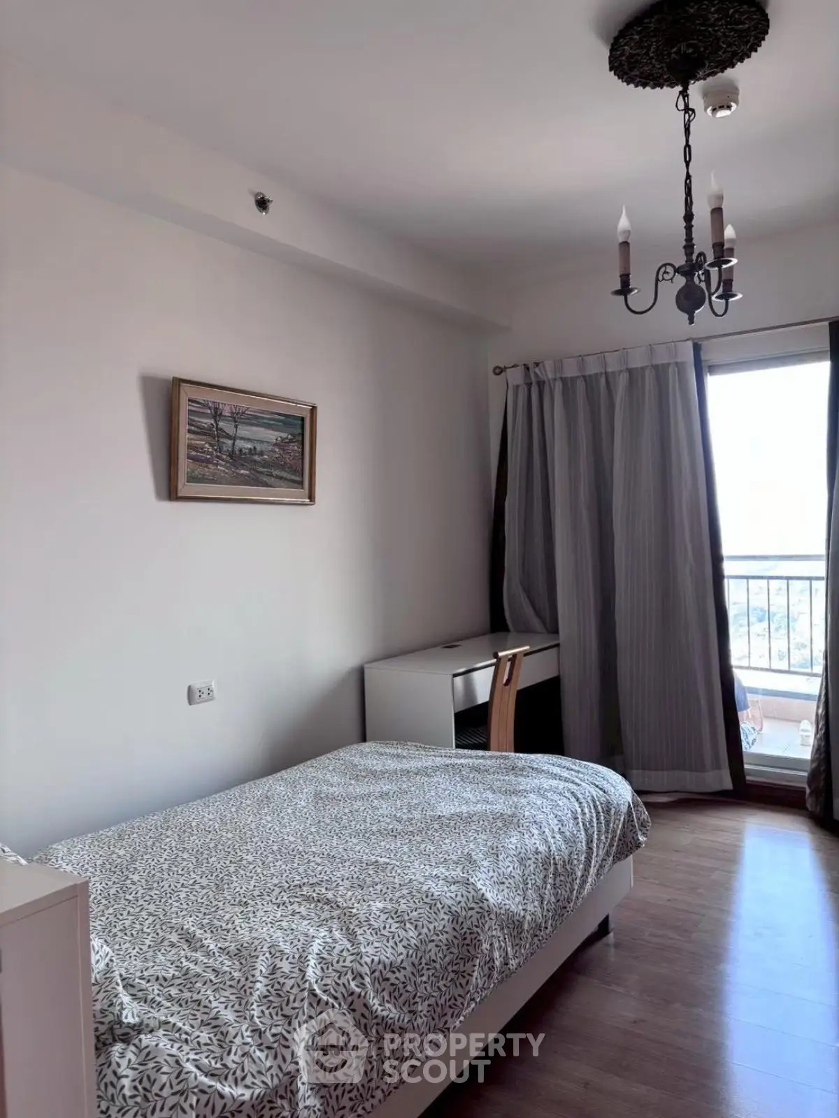 Cozy bedroom with elegant chandelier and balcony view, perfect for relaxation.