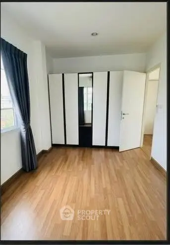Spacious bedroom with wooden flooring and large wardrobe, perfect for modern living.