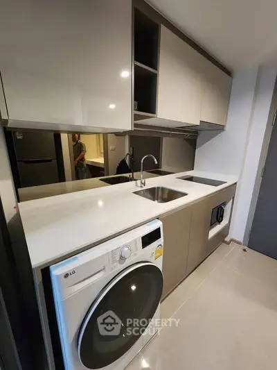 Modern kitchen with sleek cabinetry and built-in appliances, featuring a washing machine and ample counter space.