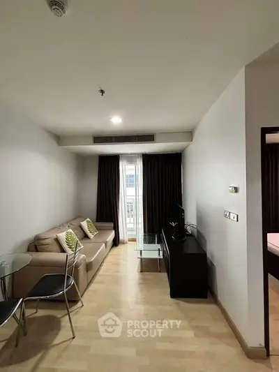 Modern living room with cozy sofa, glass table, and TV in a stylish apartment.