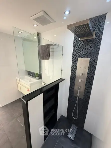 Modern bathroom with sleek shower panel and glass partition in a contemporary home.