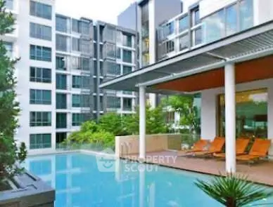 Luxurious apartment complex with modern pool and sun loungers, perfect for relaxation and leisure.