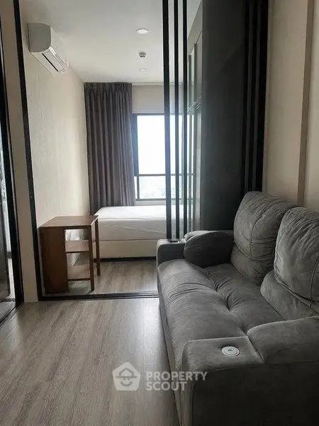 Modern studio apartment with cozy living area and bedroom separated by sliding glass doors.