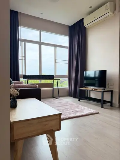 Modern living room with large window, cozy sofa, and sleek TV setup.