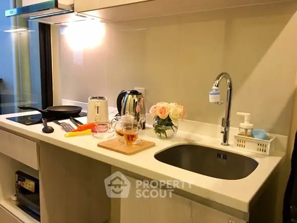 Modern kitchen with sleek countertop, sink, and appliances in stylish apartment.