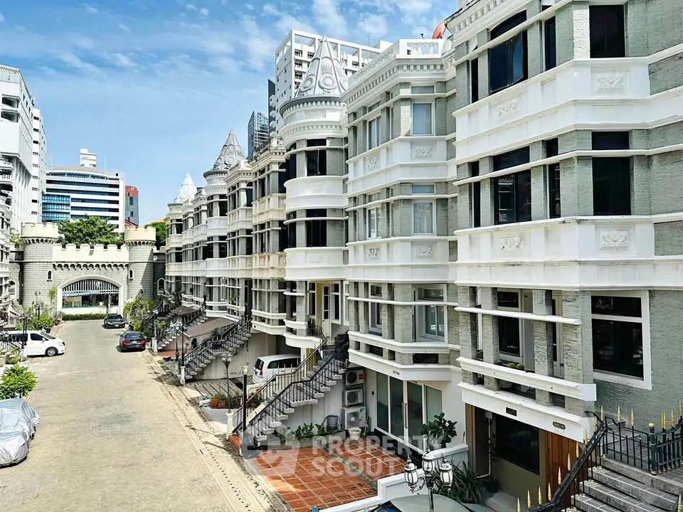 Elegant Victorian-style apartment building with ornate facade and spacious parking area.