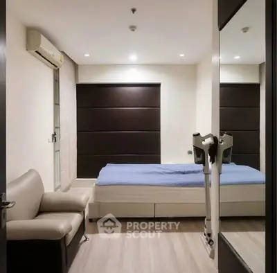 Modern bedroom with sleek design, featuring a comfortable bed, stylish sofa, and air conditioning unit.
