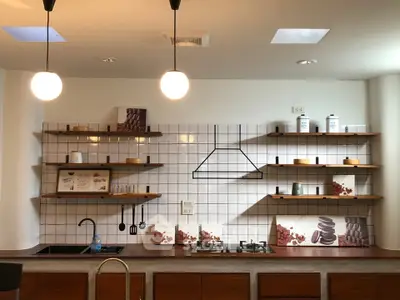 Modern kitchen with open shelving and gas stove, featuring stylish lighting and contemporary design.