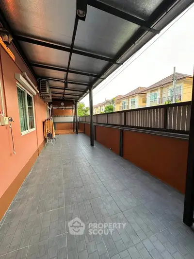 Spacious covered balcony with tiled flooring and residential view, perfect for outdoor relaxation.