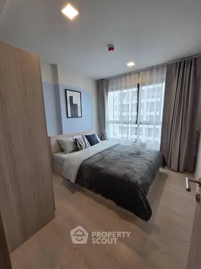 Modern bedroom with stylish decor and large window offering natural light