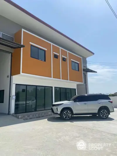 Modern two-story building with large windows and parked SUV in driveway