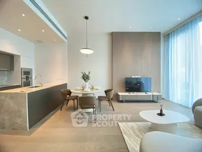 Modern open-plan living room with elegant kitchen and dining area, featuring sleek furniture and large windows.