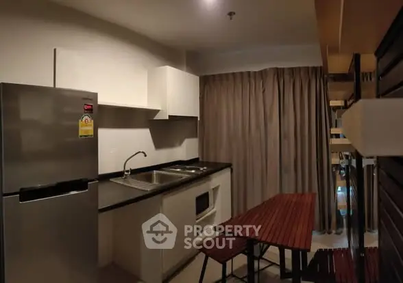 Modern kitchen with sleek appliances and dining area in cozy apartment