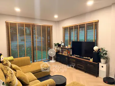 Cozy living room with stylish furniture and large windows with wooden blinds.