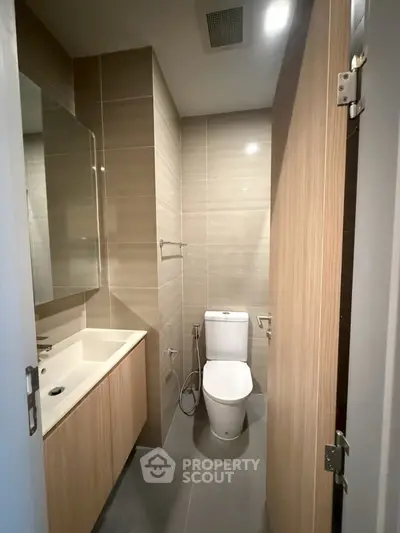 Modern bathroom with sleek design and neutral tones, featuring a toilet and vanity unit.