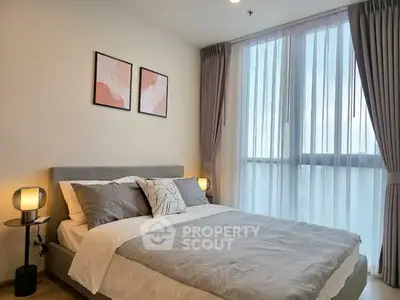 Modern bedroom with large window and stylish decor in a cozy apartment.