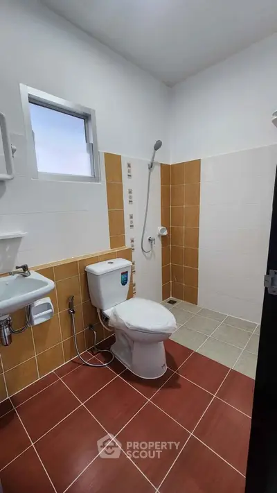 Modern bathroom with tiled walls and floor, featuring a shower and toilet.