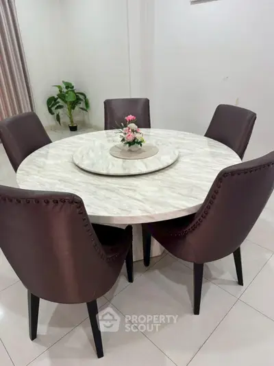Elegant dining area with round marble table and stylish chairs, perfect for modern interiors.