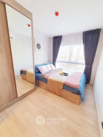 Spacious bedroom with large window and modern decor, featuring a comfortable bed and stylish curtains.