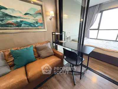 Modern studio apartment with cozy living area and stylish bedroom separated by glass partition.