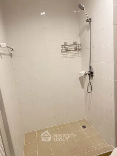 Modern bathroom shower area with sleek tiles and handheld showerhead