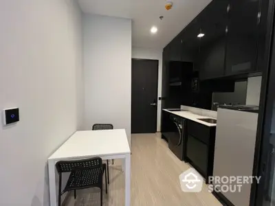 Modern compact kitchen with sleek black cabinets and integrated appliances in a stylish apartment.