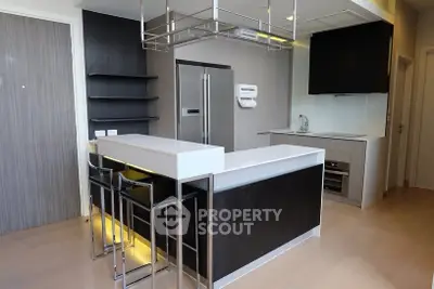 Modern kitchen with sleek design, featuring an island, stainless steel appliances, and open shelving.
