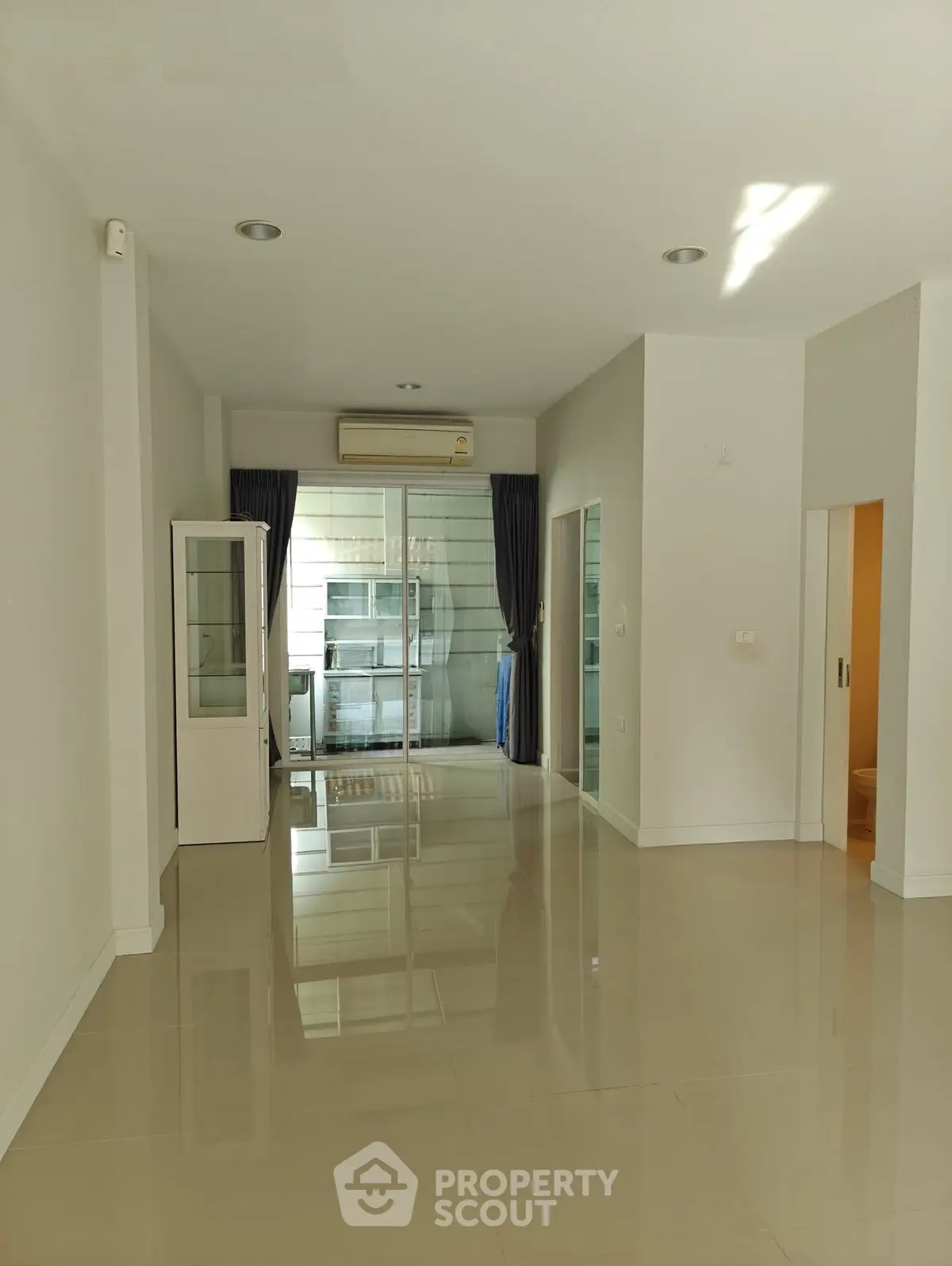 Spacious modern living room with glossy tiled floors and large windows.