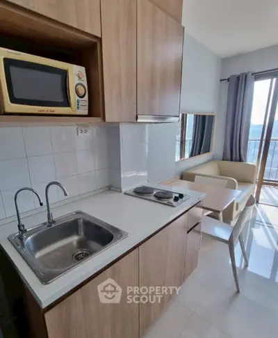 Modern compact kitchen with sleek cabinetry and dining area in bright apartment