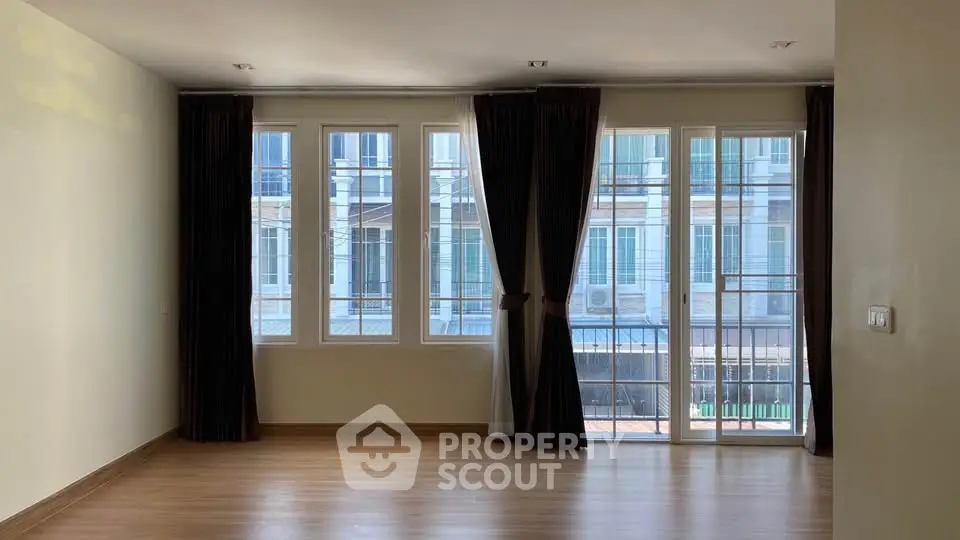Spacious living room with large windows and elegant curtains, offering ample natural light and a modern ambiance.