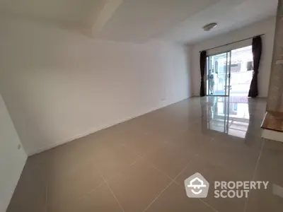 Spacious empty living room with glossy tiled floor and large sliding glass doors leading to balcony.