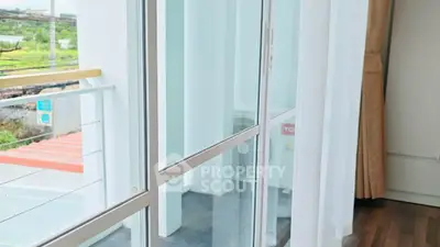 Bright balcony view with glass doors and wooden flooring in modern apartment.