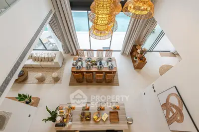 Luxurious open-plan living and dining area with pool view, featuring elegant decor and natural lighting.