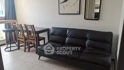 Cozy living room with black leather sofa and dining area, perfect for modern living.