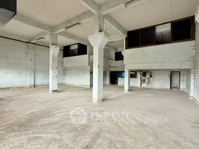 Spacious industrial warehouse interior with high ceilings and concrete pillars.