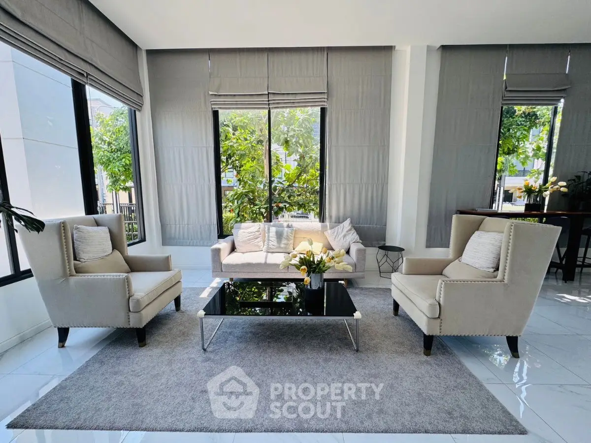 Elegant living room with modern furniture and large windows offering lush garden views.