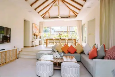 Spacious living room with modern decor and open dining area, featuring high ceilings and natural light.
