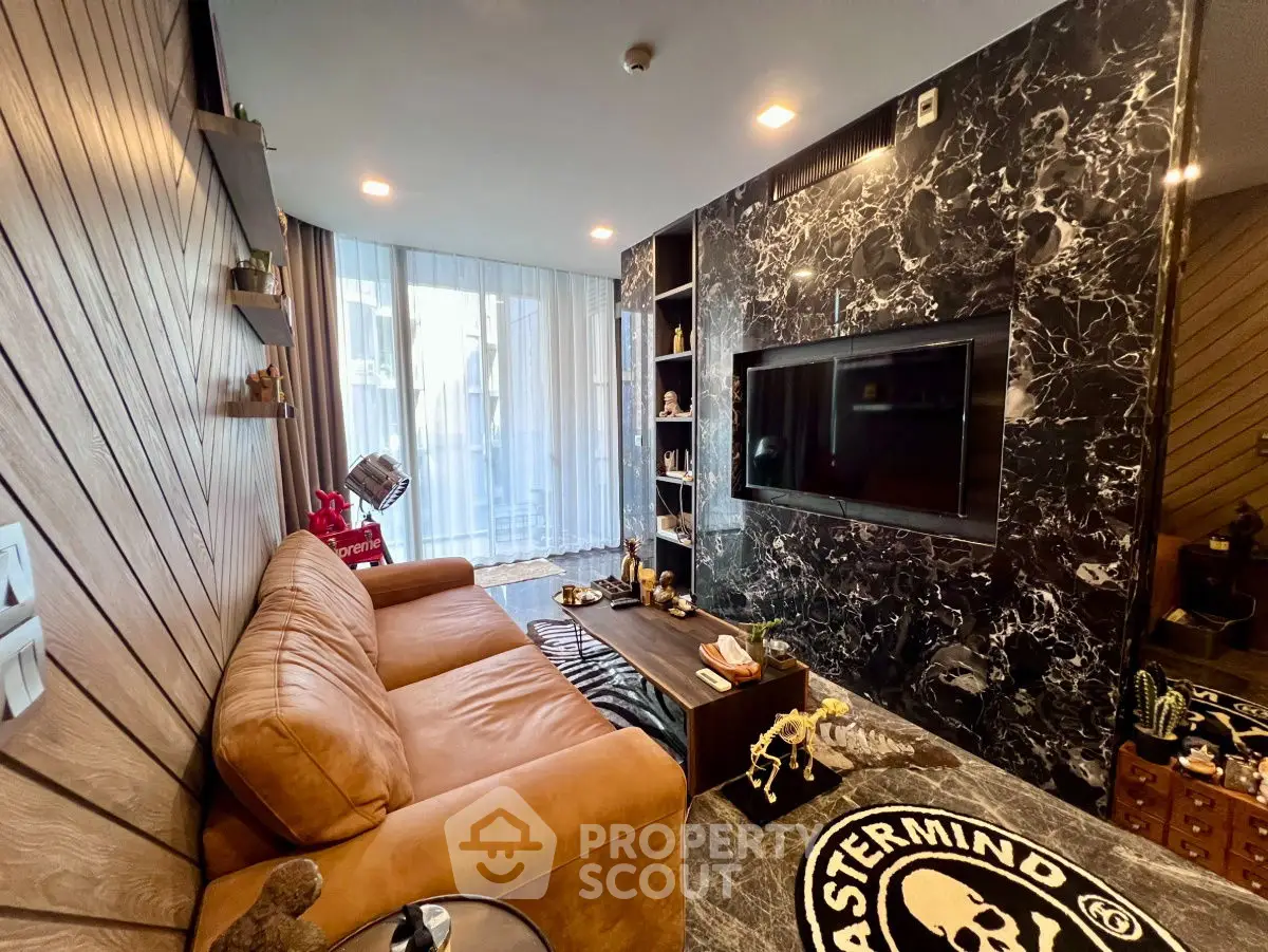 Stylish living room with leather sofa and marble accent wall featuring a large TV.