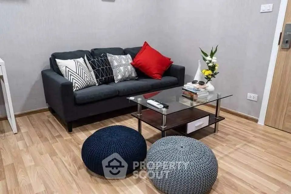 Stylish living room with modern sofa, chic decor, and cozy poufs on wooden flooring.