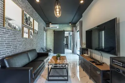 Modern living room with stylish decor, black leather sofa, and large wall-mounted TV in a contemporary apartment.