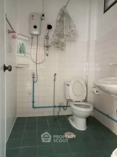 Compact bathroom with shower, toilet, and sink in a tiled setting.