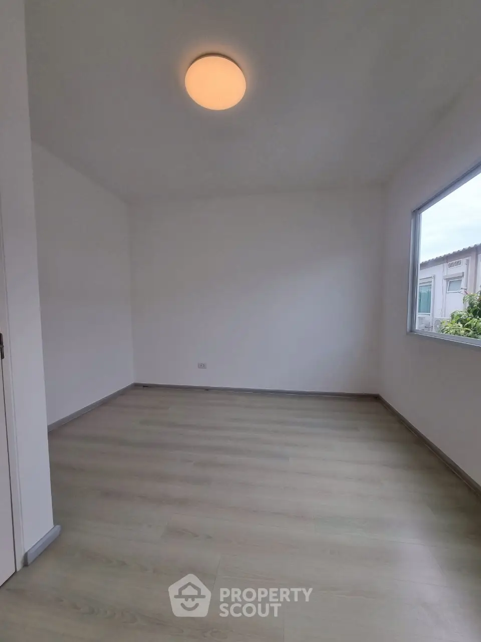 Spacious empty room with large window and modern light fixture, perfect for customization.