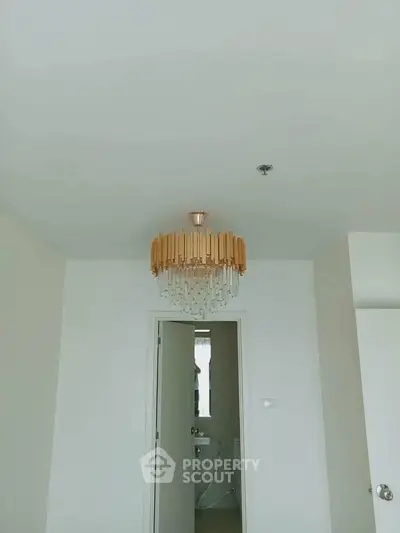 Minimalist interior with elegant chandelier and bathroom entrance, showcasing modern design elements.